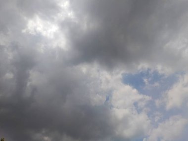 Bulutlarla dolu dramatik bir gökyüzü, içinden geçmeye çalışan güneş ışığı parıltılarıyla dolu. Sahne değişken bir hava ve güçlü bir atmosferik gökyüzü hissi uyandırıyor. Bu görüntü, değişen bir iklimin özünü, bir Da karışımıyla yakalar.