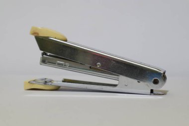 İyi giyimli eski bir zımba, metalik vücut, soluk sarı aksanlı, parlak bir arka planda oturuyor.