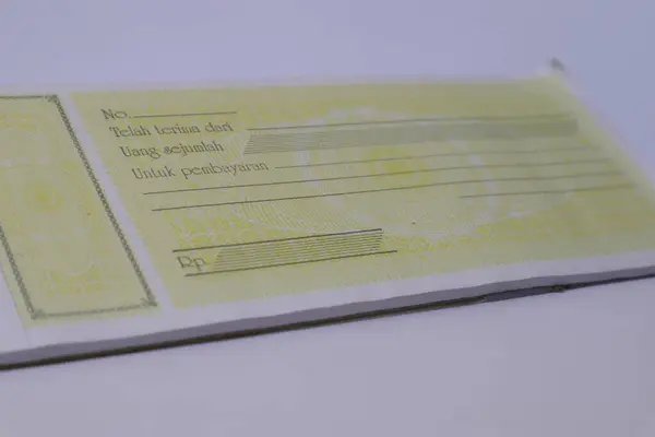 Soluk sarı bir fatura defterinin detaylı bir yakın çekimi, mali işlemleri kaydetmeye hazır..