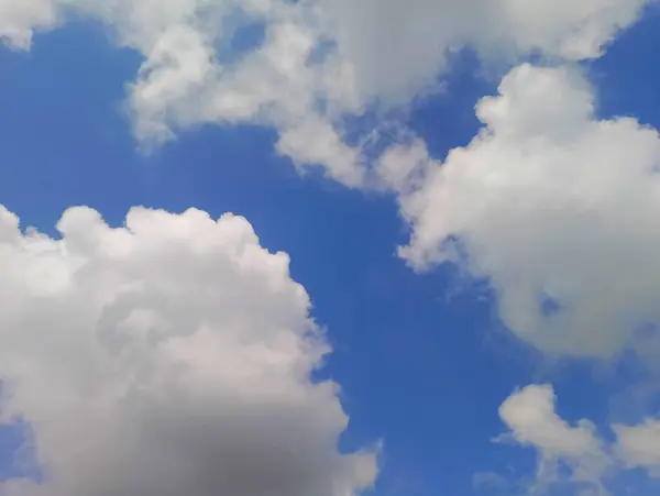 Pofuduk beyaz kümülüs bulutlarının canlı mavi gökyüzüne karşı nefes kesen görüntüsü huzur ve huzur hissi uyandırıyor..