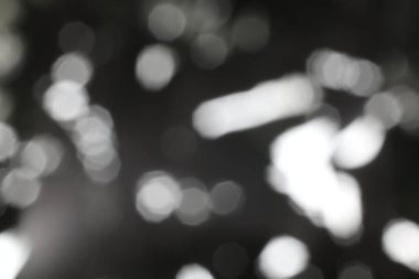 Büyüleyici tek renkli soyutlama. Yumuşak, odak dışı ışıklar karanlık bir arkaplanda dans ediyor. Büyüleyici bir bokeh etkisi yaratıyor..