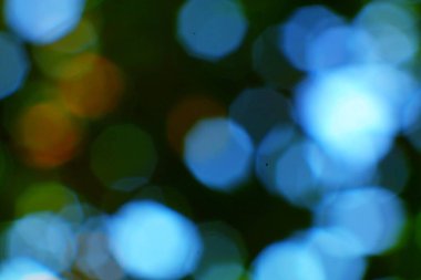 Canlı mavi, yeşil ve turuncu renklere sahip rüya gibi bir bokeh arka plan, büyülü ve yumuşak bir atmosfer yaratıyor..