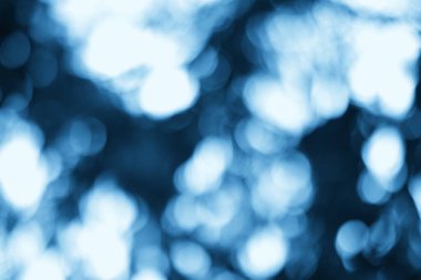 Bulanık ışık lekeleri olan soyut mavi arkaplan hayali ve ruhani bir atmosfer yaratıyor, yaratıcı tasarımlar için mükemmel.