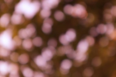 Bulanık kahverengi arkaplandan süzülen parlak pembe ışık içeren yumuşak, ruhani bir görüntü, hayali ve soyut bir doku yaratıyor..