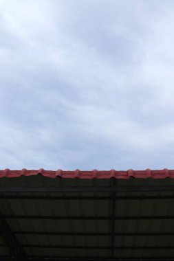 Çatı geometrisi sakin ve sessiz bir gökyüzü ile buluşuyor. Yapılandırılmış biçim ve atmosferik alan arasındaki zıtlık.