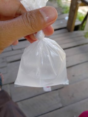 Elinde şeffaf ve ferahlatıcı sıvıyla dolu temiz bir plastik torba var.
