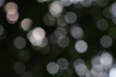 Bulanık sekizgen ışıklar, karanlık ve bulanık bir arkaplanda hafifçe parlıyor.