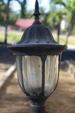 Eski süslemeli bir sokak lambası. Dokuları yıpranmış. Parkta duruyor..