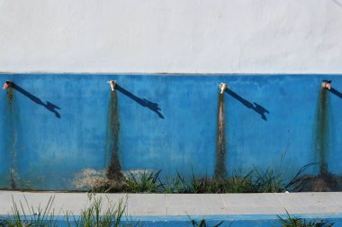 Yıpranmış mavi ve beyaz bir duvarda gölgeli kırsal açık hava muslukları