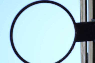 Kırsal bir demir çember yumuşak bir gökyüzünü çerçeveler, yansımayı ve minimalist tasarımı çağrıştırır.