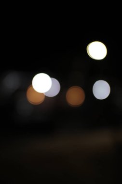 Beyaz, kahverengi ve gri tonlarında bulanık bokeh ışıklarının bir derlemesi, siyah bir arkaplana karşı nazik ve rahatlatıcı bir atmosfer yaratır.