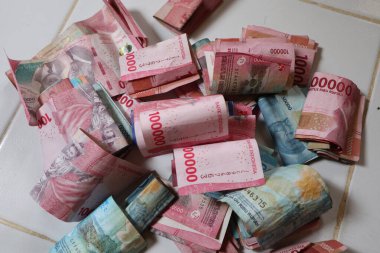 Endonezya Rupiah banknotlarından oluşan dağınık bir koleksiyon finansal kazançları, zenginlik birikimlerini ve hafif bir arkaplanda yapılan parasal işlemleri temsil ediyor.