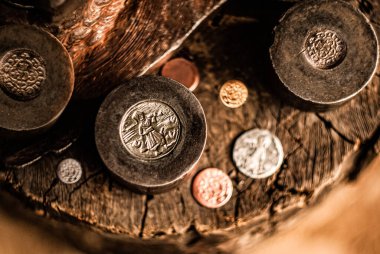 Antika bir madeni para basma makinesinin ve çeşitli oymalı paraların yakın plan görüntüsü geleneksel para yapma sürecinin ayrıntılı işçiliğini gözler önüne seriyor..