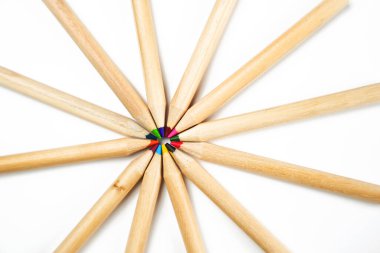 Tahta kalemler, uçlarıyla birlikte beyaz bir yüzeyde renkli bir merkezde toplanır. Kompozisyon kalemlerin çeşitli uzunluklarını ve renklerini vurgular.