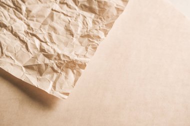 Buruşuk kahverengi kağıt yumuşak, nötr bir zemin üzerinde uzanıyor, desenli yüzeyi ve organik kıvrımlarını vurguluyor. Sıcak melodiler rahatlatıcı bir görsel etki yaratır..