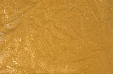 Zengin bir altın yüzey, ışığı güzel bir şekilde yakalayan çeşitli doku ve desenleri sergiler. Sıcak bir atmosferde göz alıcı bir görsel deneyim yaratır..