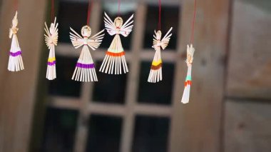 Doğal malzemelerden yapılmış parlak renkli melekler geleneksel bir pazarda asılı duruyor. Festival atmosferi, yerel kültür ve sanatın özünü yansıtıyor..