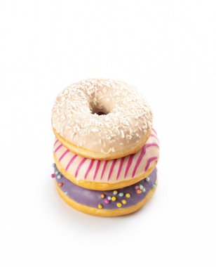 Üç yeni yapılmış donut bir araya toplanmış, mor krema, renkli serpinti ve hindistan cevizi kaplı jöle gibi canlı malzemeler, her durum için mükemmel bir davet yaratıyor..