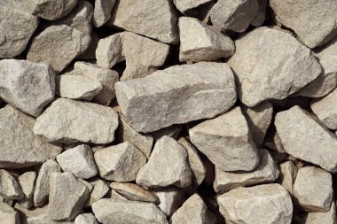 Pürüzsüz, düz olmayan açık renkli çakıl parçaları alanı dolduruyor ve çeşitli şekil ve boyutlarda sergiliyor. Güneş ışığı onların dokusunu ön plana çıkarır ve dünyevi bir sahne yaratır..