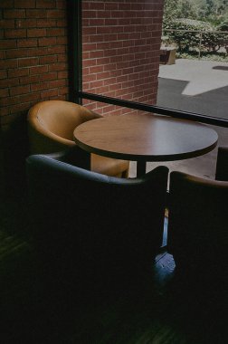 Modern ofis sandalyeleri seti ve doğal güneş ışığıyla aydınlatılmış geniş bir pencereye yerleştirilmiş bir masa.