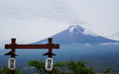 Klasik bir Japon feneriyle çerçevelenmiş ve sakin manzarayla çevrili Fuji Dağı 'nın ikonik karla kaplı zirvesine bakın.
