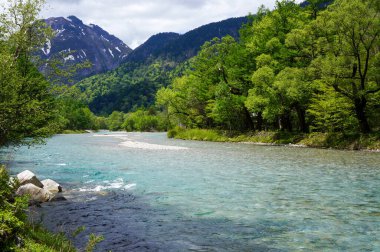 Görkemli, karla kaplı zirvelerle çevrili bir vadide el değmemiş bir nehrin esintisi gibi güzel bir manzara beliriyor. Doğanın huzur veren güzelliği.
