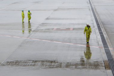 Suwannabhumi Havaalanı, Samutprakarn, Tayland - 30 Mayıs 2025: Kendini adamış bir ekip, güvenlik giysileri içinde, bir havaalanı aparatının geniş, nemli alanlarında geziniyor.
