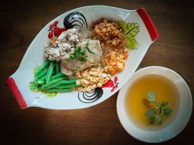 Thai Cha Kang Rao, kıymalı beyaz şehriye, domuz derisi dilimlenmiş fasulye ve ahşap masa dokusunda oyuk desenli culantro.