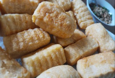 Arka planda küçük bir sos tabağı ve bir tabakta kızarmış tofu kalıpları yakın plan..