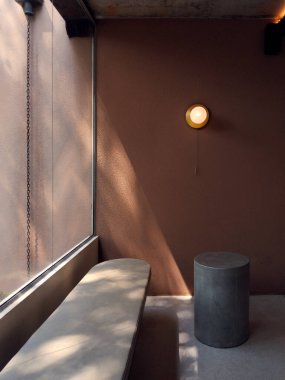 Beton bir bank, silindir bir tabure ve sıcak ışıklandırmayla minimalist iç mekan..