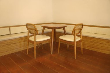 Ahşap sandalyeler ve masa şık bir kafe köşesinde, rahat bir iç mekanı var.