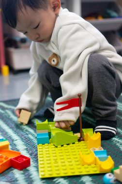 İki yaşındaki Asyalı çocuk renkli yapı taşları oyuncağının keyfini çıkarıyor.