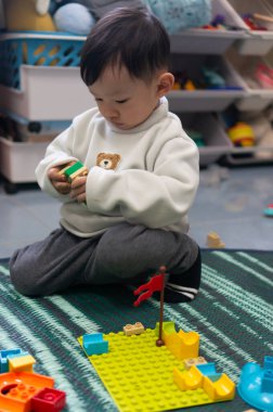 İki yaşındaki Asyalı çocuk renkli yapı taşları oyuncağının keyfini çıkarıyor.