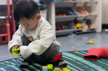 İki yaşındaki Asyalı çocuk renkli yapı taşları oyuncağının keyfini çıkarıyor.