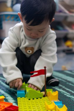 İki yaşındaki Asyalı çocuk renkli yapı taşları oyuncağının keyfini çıkarıyor.