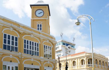 Tayland 'da güneşli bir Phuket Adası' nda kemerli camları ve sokak lambası olan tarihi bir sarı saat kulesi..