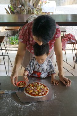 Bir kadın ve bir çocuğun kalp ısıtan sahnesi, birlikte lezzetli bir pizza pişirmenin hazzına dalmış..