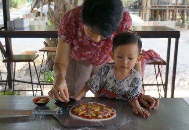 Bir kadın ve bir çocuğun kalp ısıtan sahnesi, birlikte lezzetli bir pizza pişirmenin hazzına dalmış..