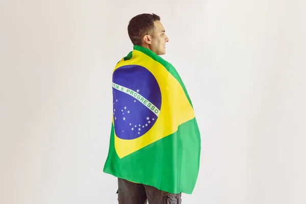 サッカーチームとブラジルの旗を保持黒人男性黄色のシャツ白に隔離された ブラジルがチャンピオンになるためのスポーツファン応援 — ストック写真