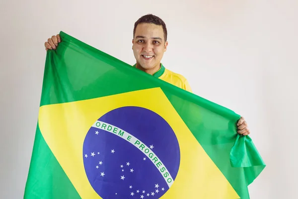 Black Man Holding Brazilian Flag With Soccer Team Yellow Shirt Isolated on White. Sport Fan Cheering for Brazil to be the champion.