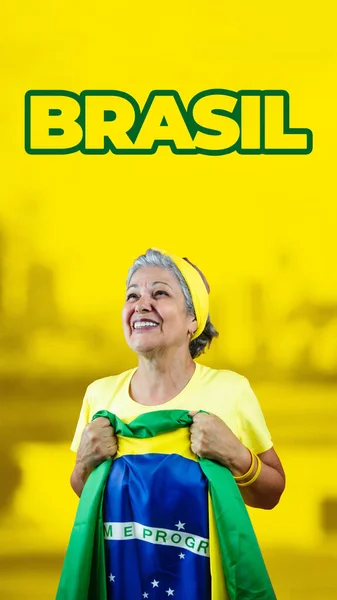 在电影背景上高举巴西国旗的漂亮老年妇女 适用于有复制空间的社交媒体 — 图库照片
