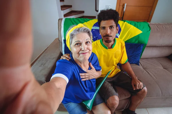 母親と息子ブラジルのためのテレビ応援を見てリビングルームでカップを祝います カップゲームを見ながら自撮り写真を撮るミックスレースファミリー — ストック写真