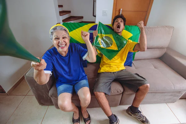 Mother and Son Celebrating the Cup in the living room watching TV cheering for Brazil. Mixed Race Family taking selfie photo while watching cup game.