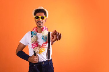 Carnival Brazilian Outfit. Black Man With Carnival Costume Pointing, Isolated on Orange Background