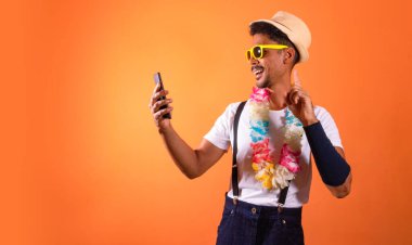 Carnival Brazilian Outfit. Black Man With Carnival Costume Holding Mobile,  Isolated on Orange Background