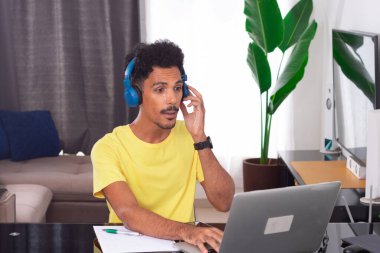 Black Man Wearing Yellow T-shirt at Remote Job in His House. clipart