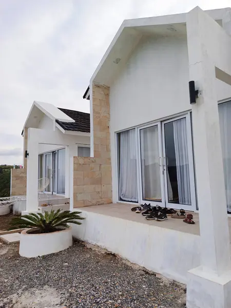 Ön planda görünen bir saksı bitkisi olan beyaz bir misafir evi Alahan Panjang, Batı Sumatra 'da..