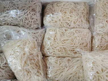 Plastik torbalarda bir sürü beyaz erişte var. Çantalar üst üste istiflenmiş.