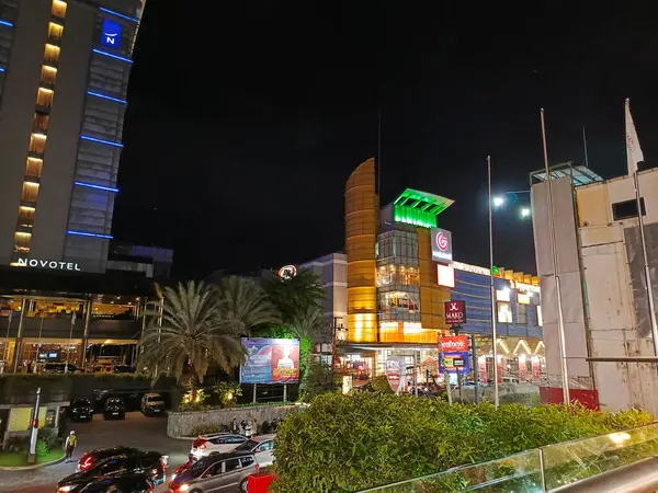 Pekanbaru, Endonezya - 28 Ocak 2025: Bir alışveriş merkezi ve bir otelin yer aldığı gece şehir manzarası.