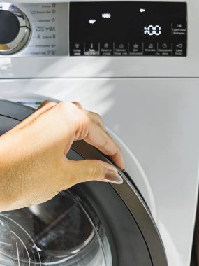 Hizmetçi evdeki çamaşır makinesine kirli çamaşır koydu. Annem çamaşırları evde çamaşır makinesine dolduruyor. Yurtiçi Ev Bakımı.